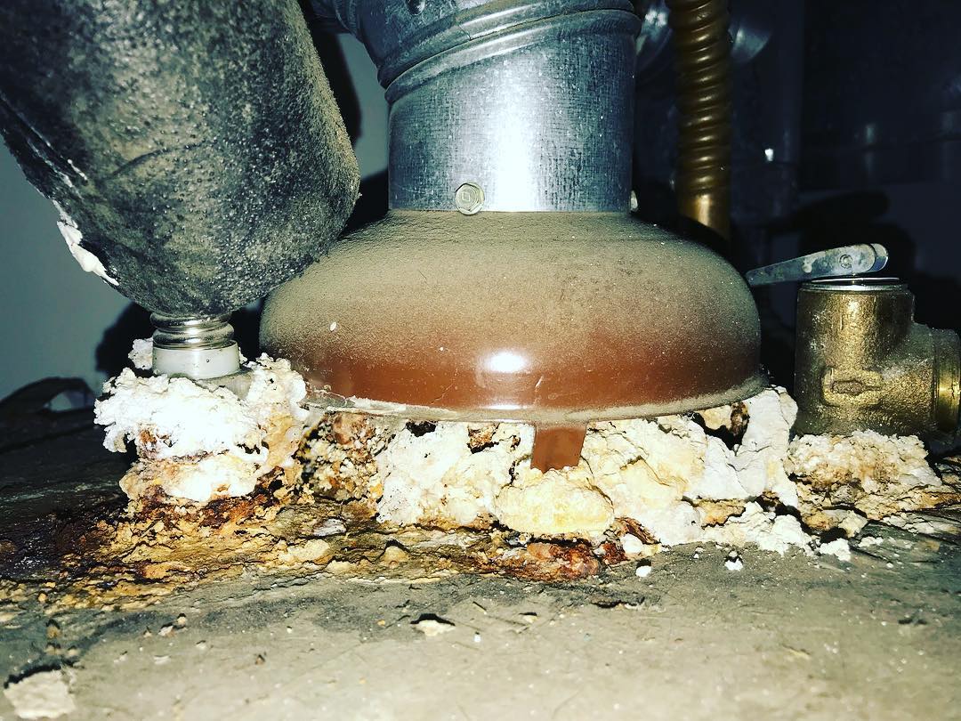 Severe corrosion and mineral deposits around water heater flue observed during a home inspection in Escondido, California